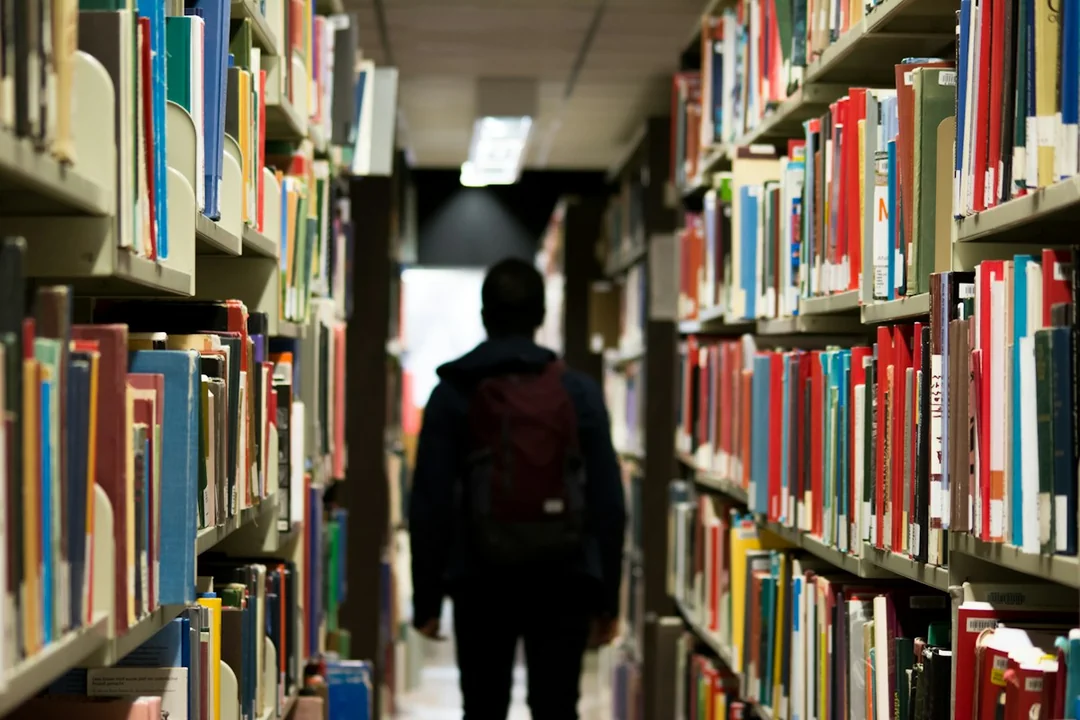 A person walking between library bookshelves