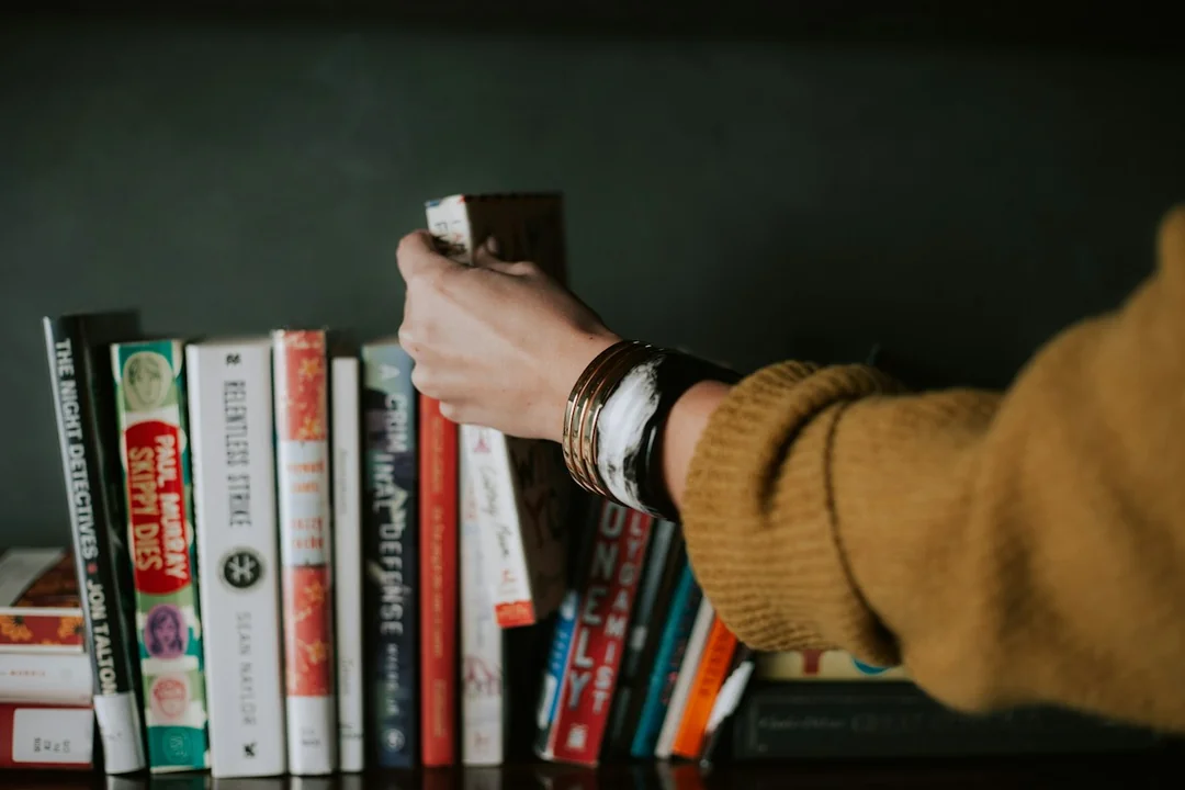 A hand selecting a book from a shelf