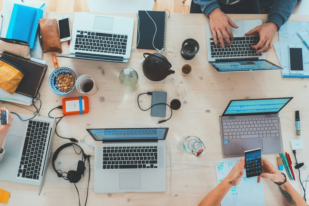 A shared table with laptops and notebooks